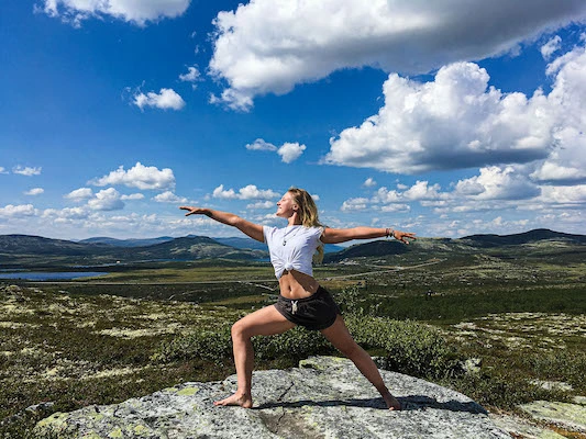 A woman practices yoga outside in a mountain landscape