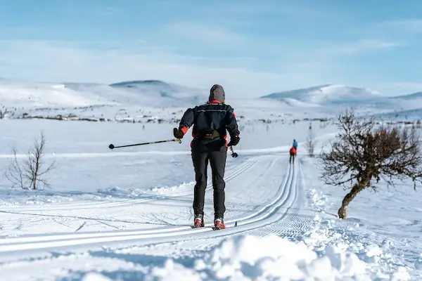 A female cross country skier double poles away from the camera