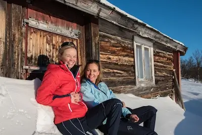 two women relaxing next to a cabin Venabygdsfjellet