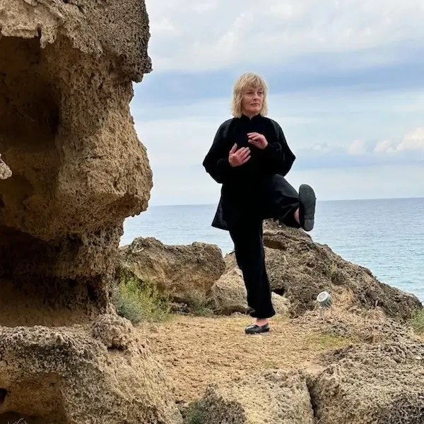 Woman practices Tai Chi by the sea